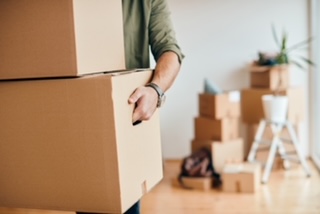 Close-up of a man with carton boxes moving into new home.